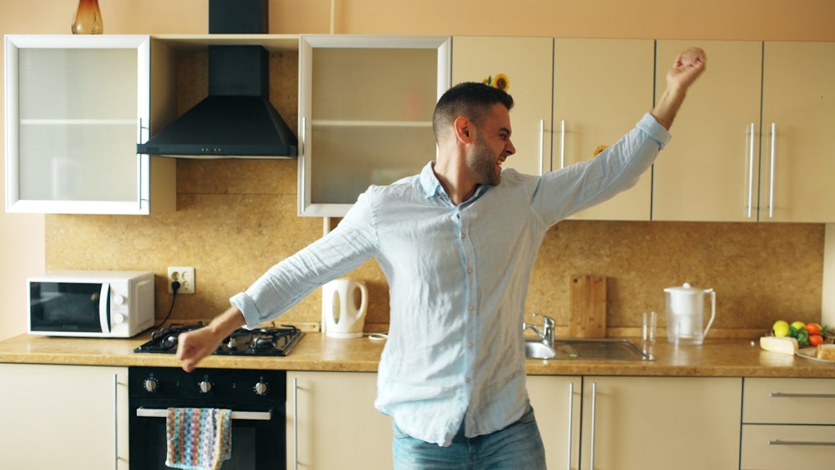 Handsome young funny man dancing in kitchen at home in the morning and have fun on vacation
