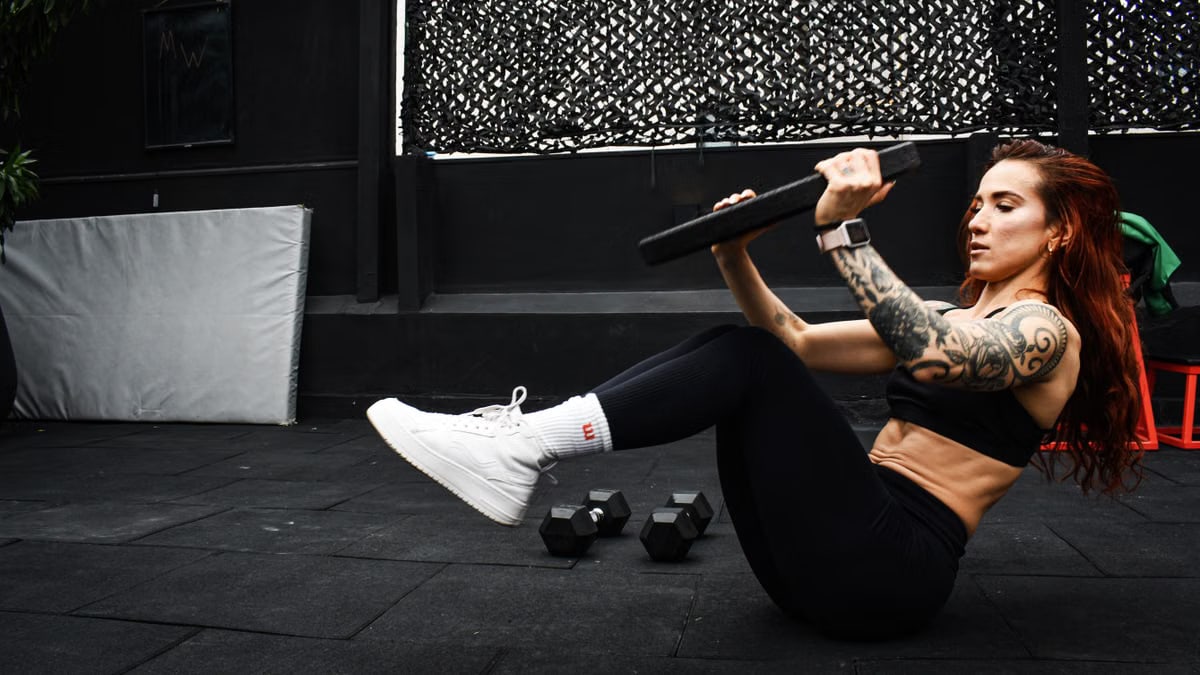 A determined woman performs a core workout in an indoor gym setting.